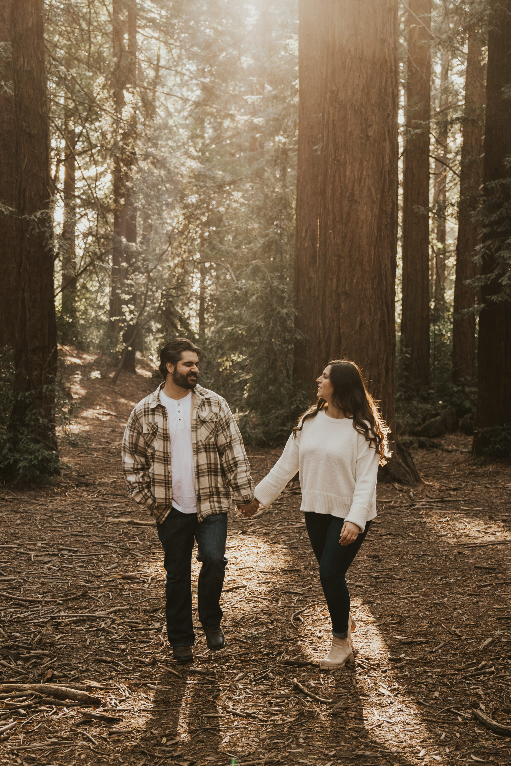 Newly engaged couple walks hand in hand in the Oakland Redwood forest