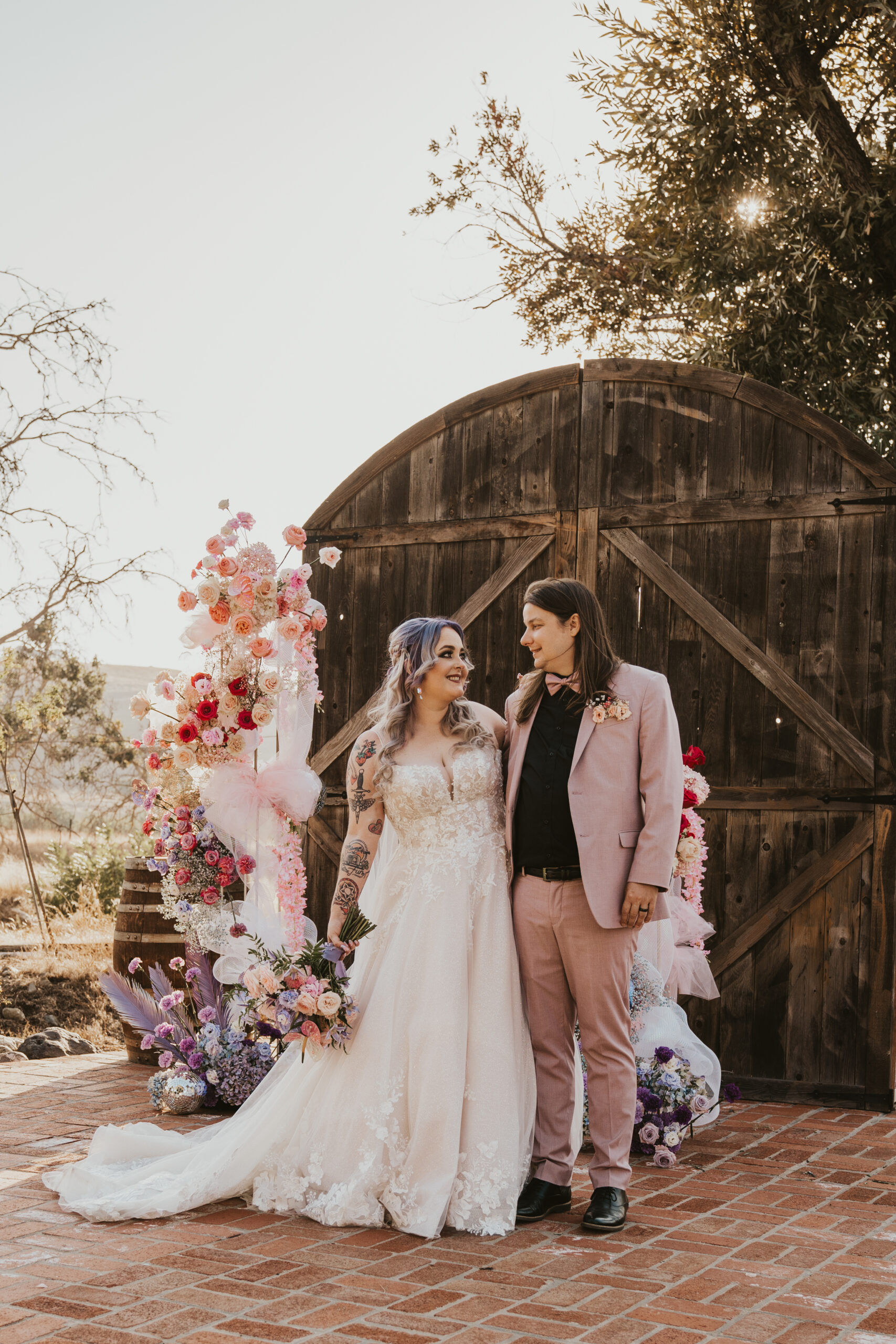Newlywed couple standing in front of floral arrangements at altar after wedding in Livermore, California wine country during golden hour